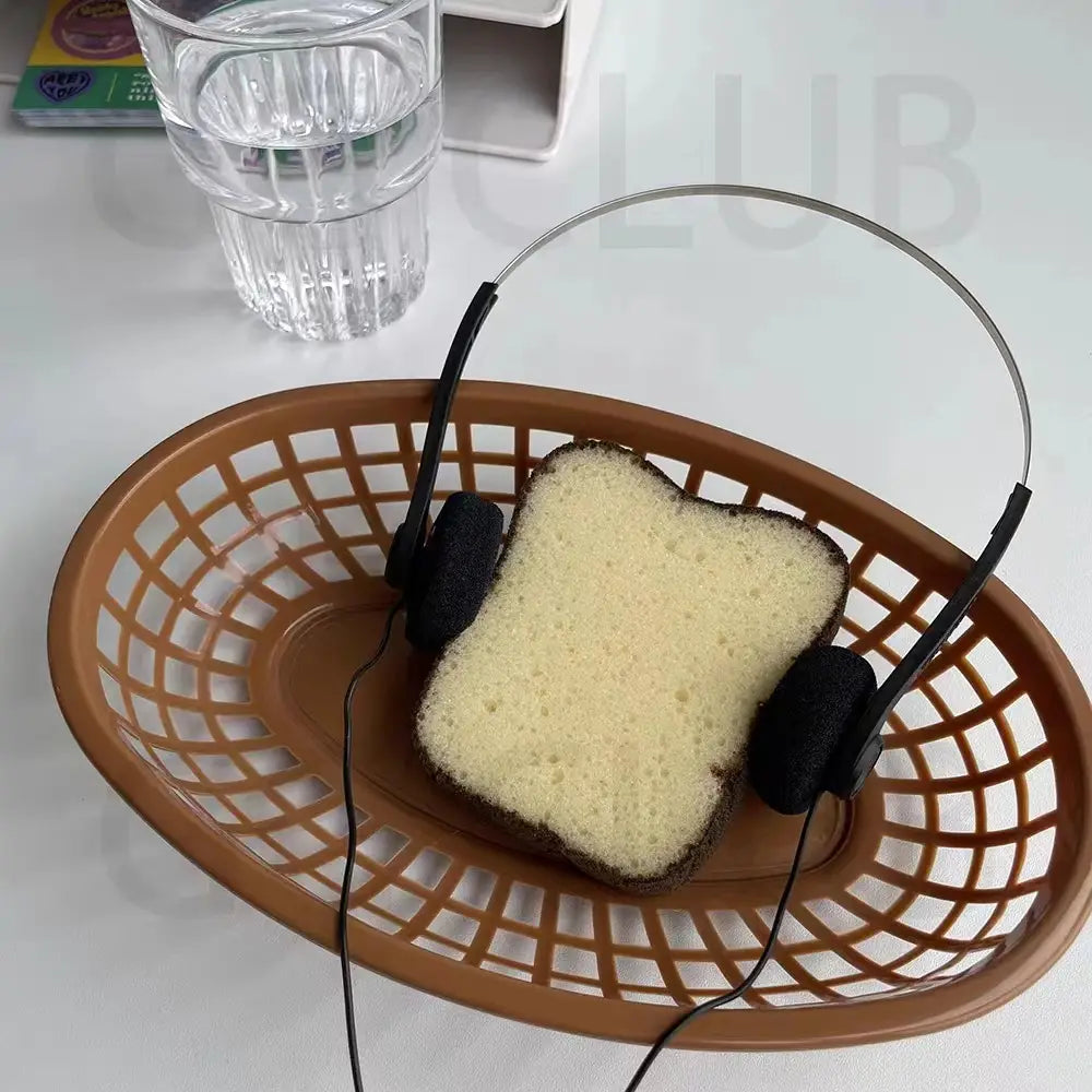 Eine Scheibe geröstetes Brot mit dunkler Kruste und hellem Inneren, die in einem braunen Plastikkorb liegt und kleine Kopfhörer trägt, retro, kabelgebunden, tragbar, schwarz.