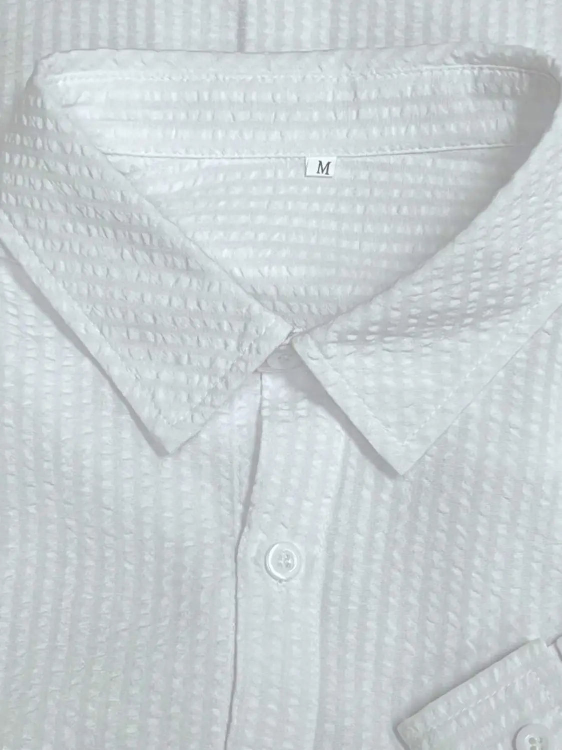 Chemise décontractée boutonnée manches longues à rayures bleues pour homme, en coton blanc à texture gaufrée, avec col classique et boutons assortis.