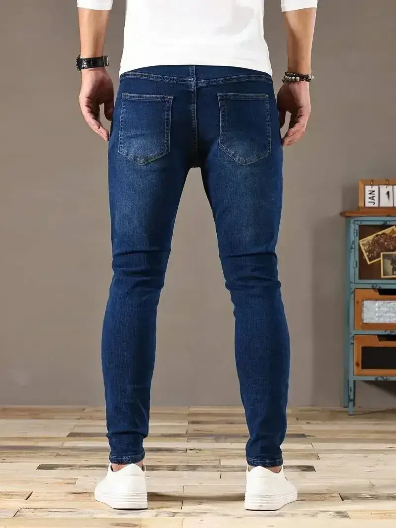 Jeans en denim bleu foncé coupe slim pour homme présentant un design classique à cinq poches, réalisé dans une matière denim résistante.