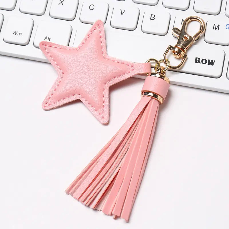 Pink star-shaped leather keychain for women with a matching tassel and gold-tone metal clasp.