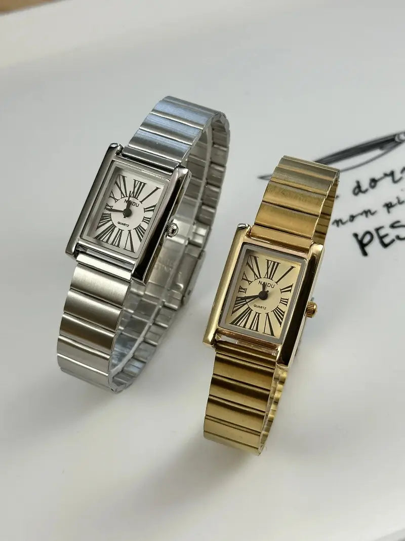 Two rectangular-faced quartz watches for women featuring one silver-tone metal with a white dial and roman numerals and one gold-tone metal with a cream-colored dial and matching roman numerals in a vintage gold rectangular quartz watch collection.