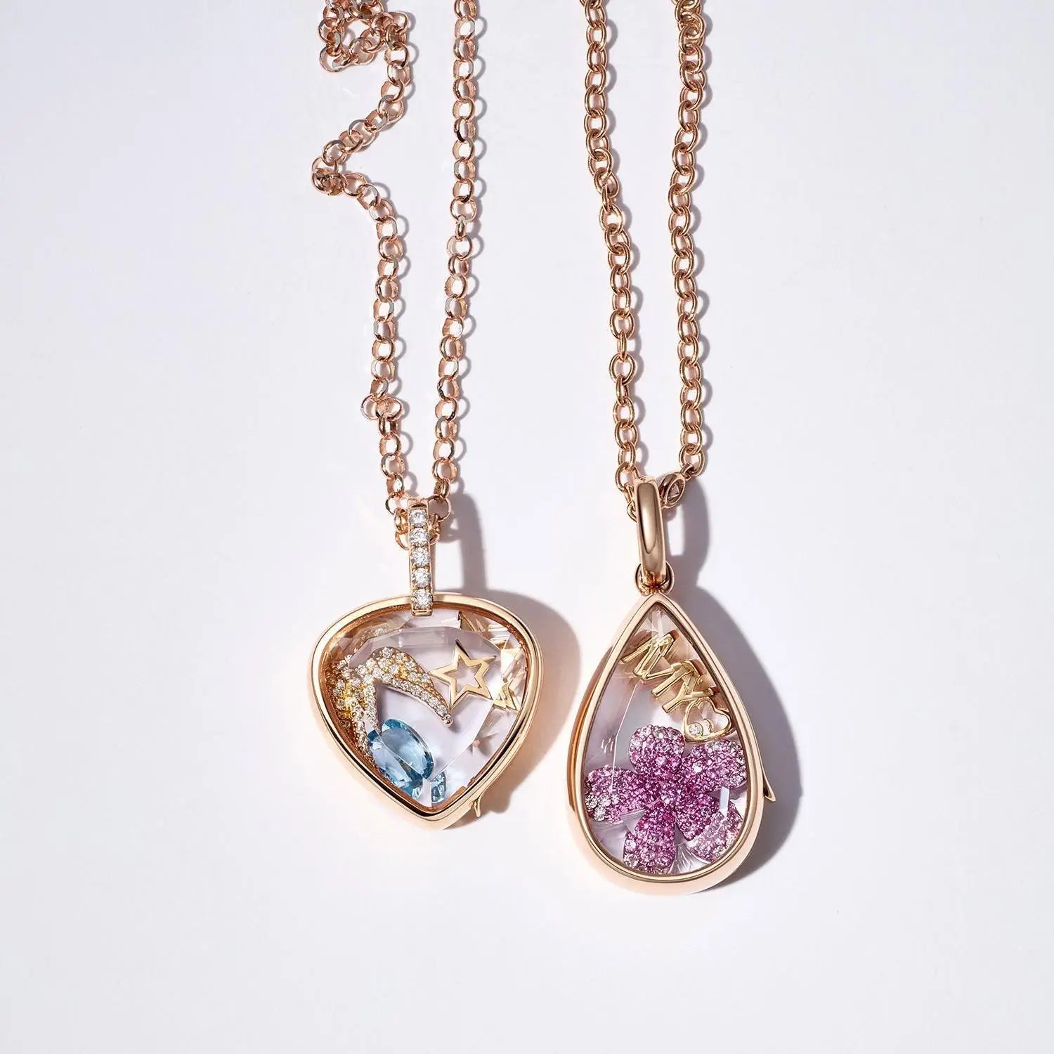 Deux colliers pendentifs ouverts ton or rose pour femmes et jeunes filles, style simple, avec des médaillons en forme de cœur et de goutte, contenant des pierres précieuses colorées dans des écrins en verre transparent.