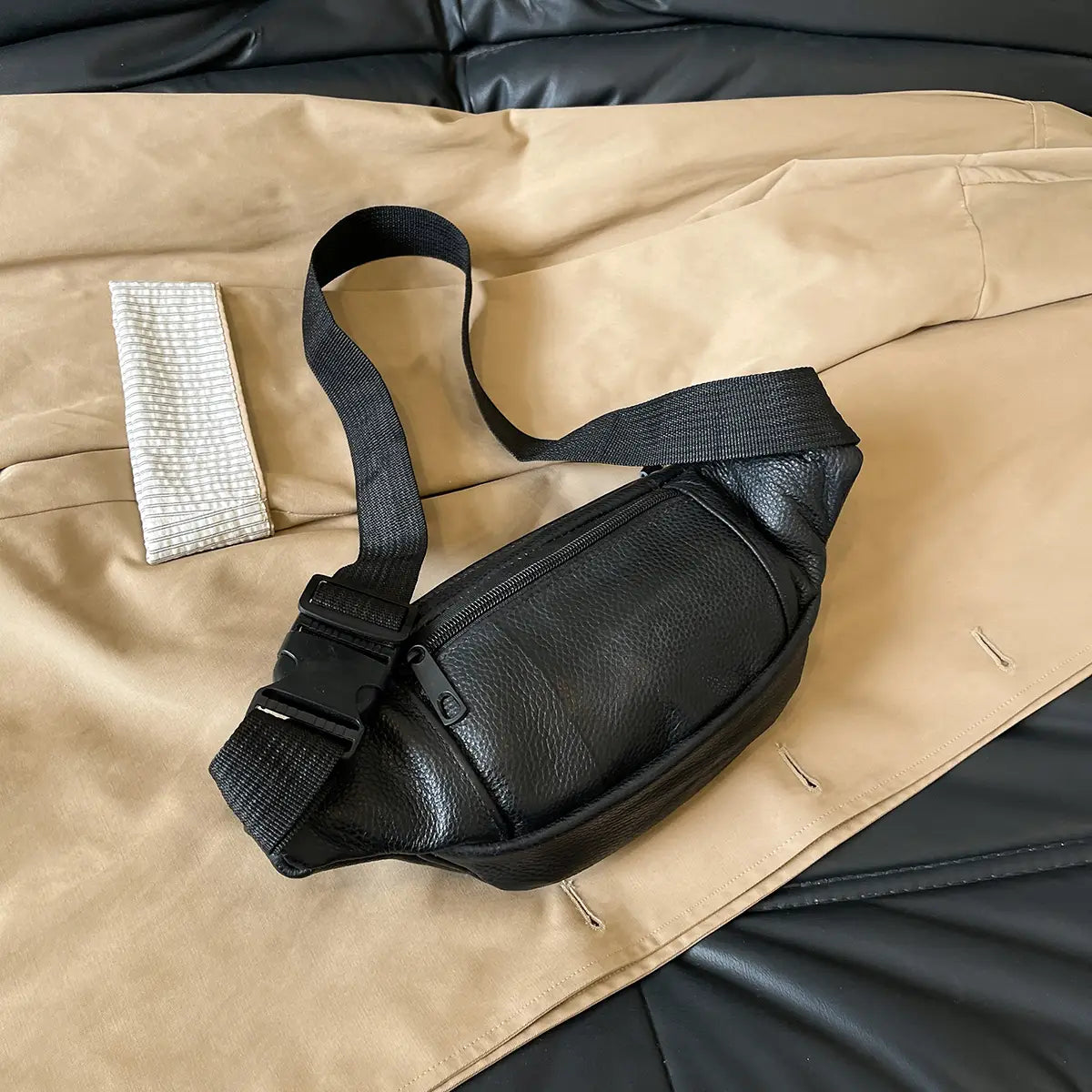 Schwarze Gürteltasche aus echtem Leder mit strukturierter Oberfläche und verstellbarem Riemen für die Verwendung als Crossbody- oder Bauchtasche.