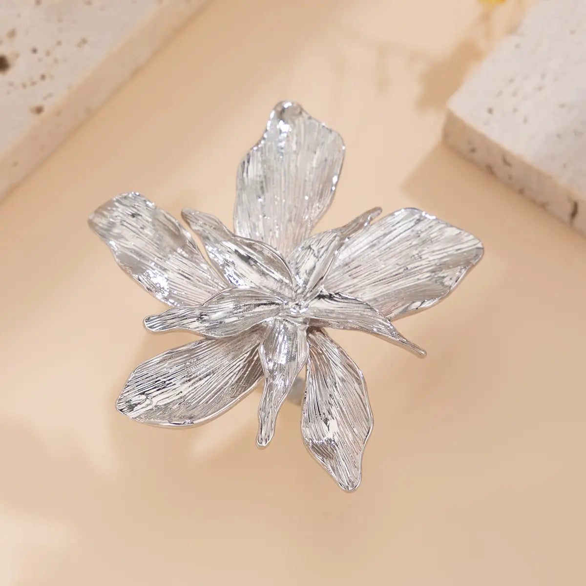 Silver metallic adjustable double layer flower ring with textured leaf like petals and intricate design.
