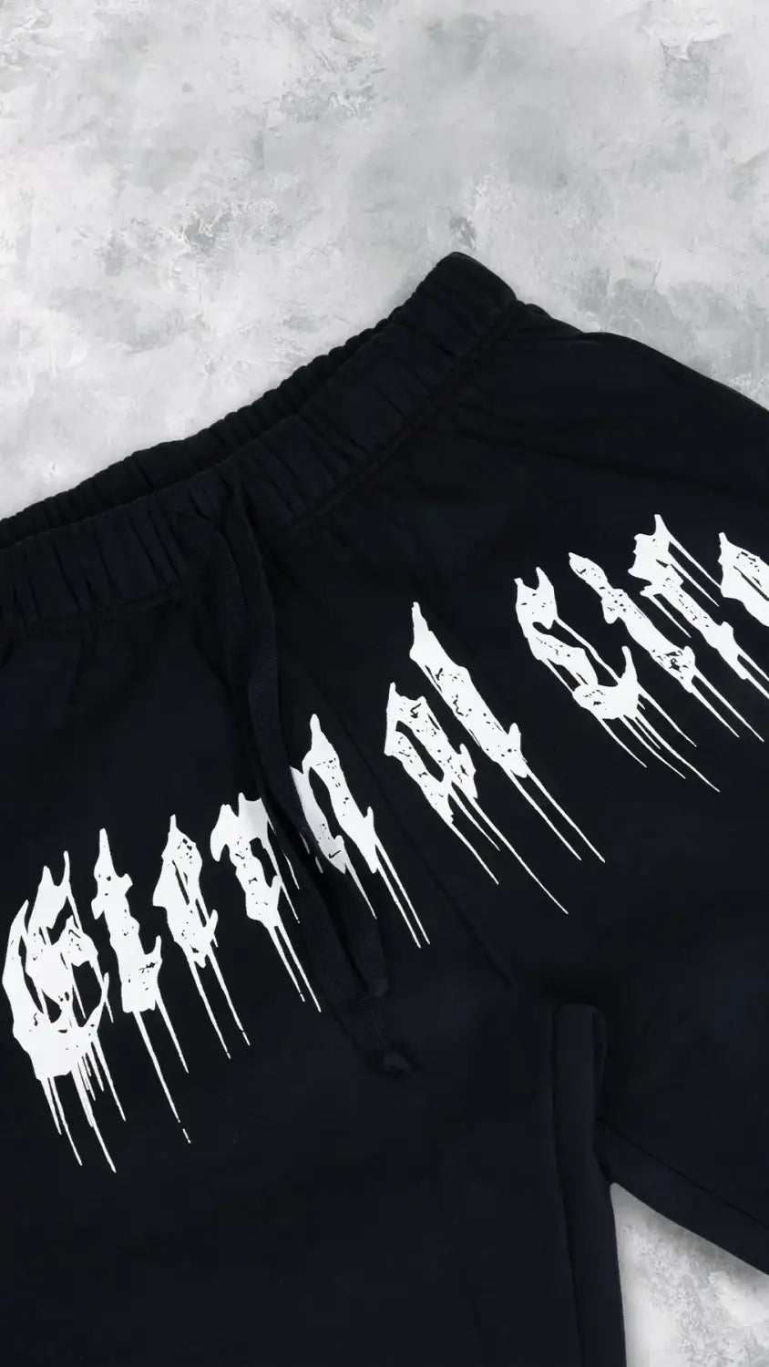 Pantalons d’entraînement graphiques pour hommes, sweatpants d’entraînement, en noir, avec une conception de police blanche audacieuse et qui s’écoule sur la jambe.