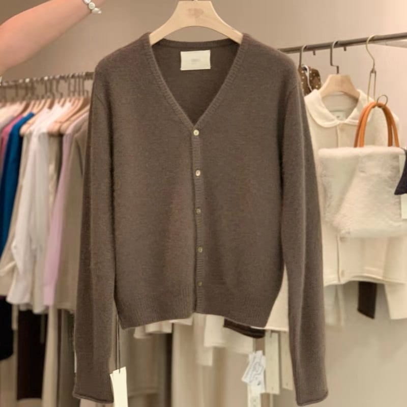 Un pull cardigan en laine mérinos brun ambré doux à encolure en V, avec un léger éclat et une fermeture boutonnée délicate.