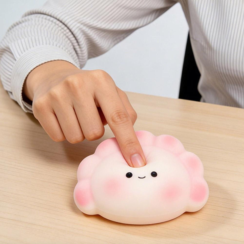 Juguete de silicona suave en color rosa con forma de dimsum para aliviar el estrés, con una linda carita sonriente, diseñado como un fidget exprimible.