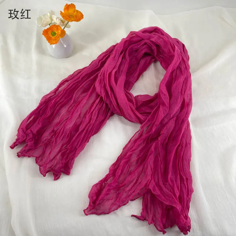 Écharpe en coton et lin plissé en mousseline de chiffon fuchsia vif, légère, avec une texture légèrement froissée et des bords effilochés.