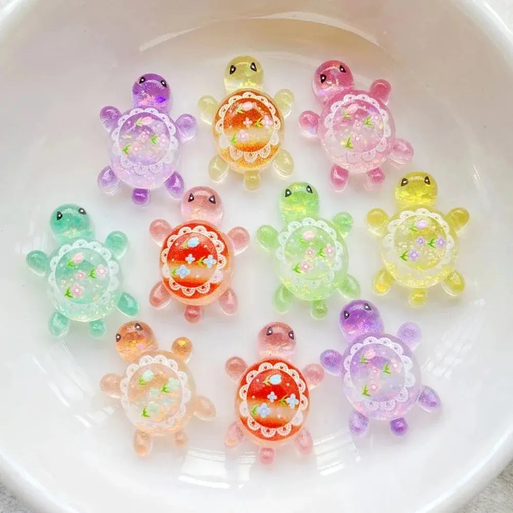 Colorful translucent resin turtle flatback charms with delicate lace-like patterns and embedded floral designs in a 10 pack.