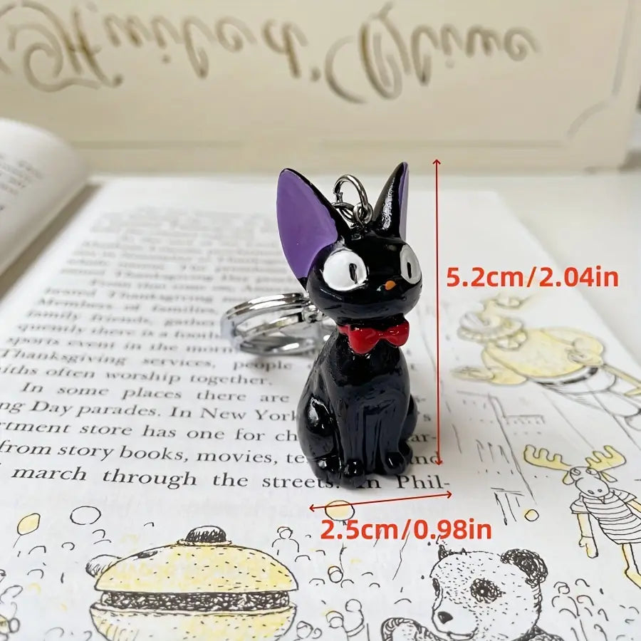 Black cat keychain with purple ears white eyes and red bow tie made of cute PVC used as a bag charm.