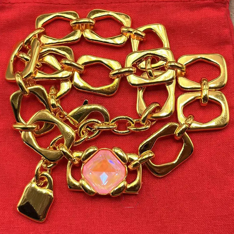 Gold-toned chain bracelet from the crystal pendant jewelry set featuring a prominent pink faceted gemstone charm and matching padlock pendant in gold and silver tone.