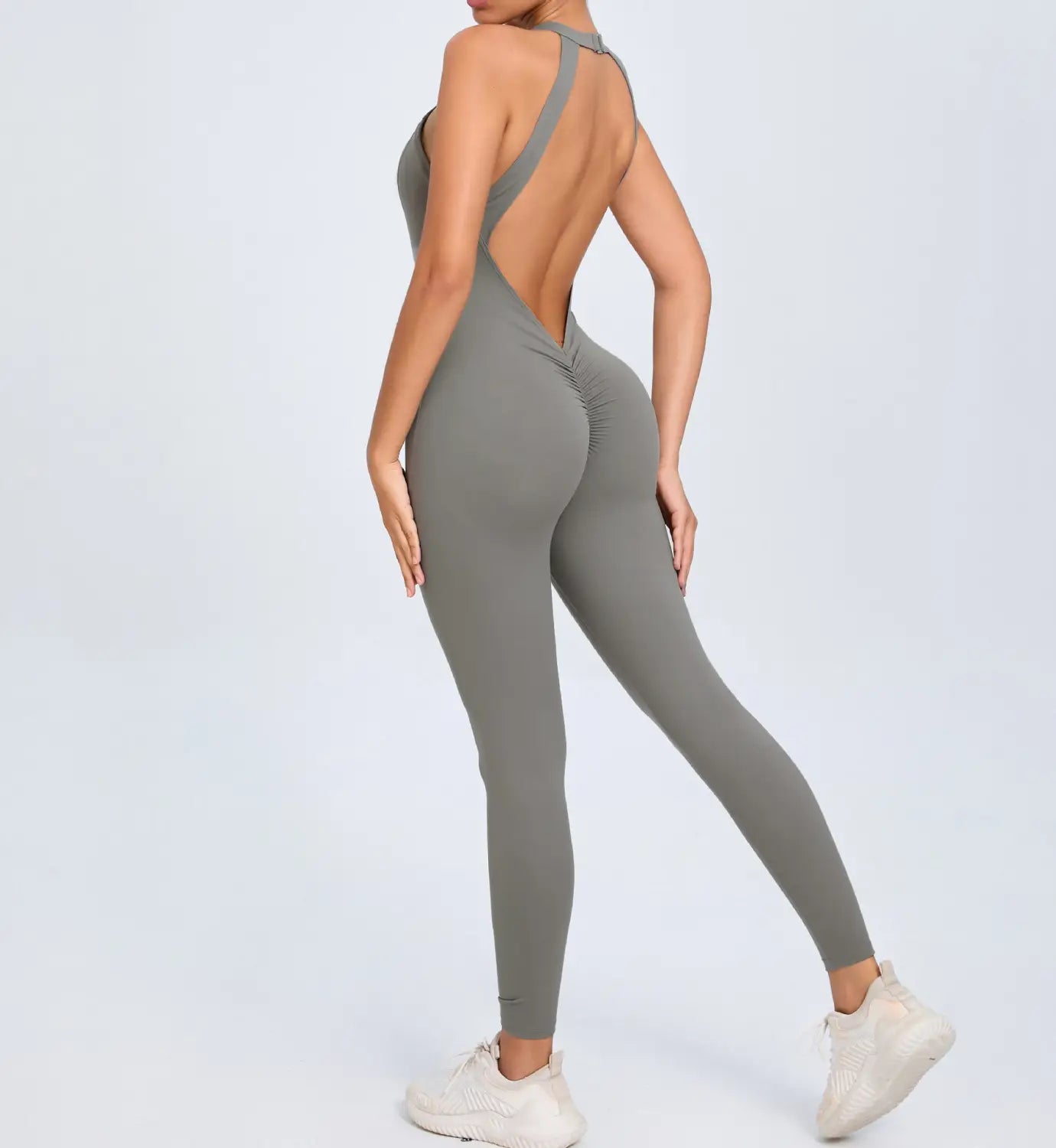 a sleek olive-green one-piece athletic jumpsuit with a high-neck back and ruched detailing shown from the back for workout use