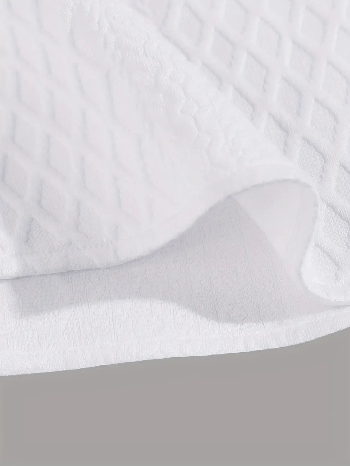 tissu blanc texturé avec un motif matelassé à motifs de losanges utilisé pour un haut gris en maille diamant à manches courtes