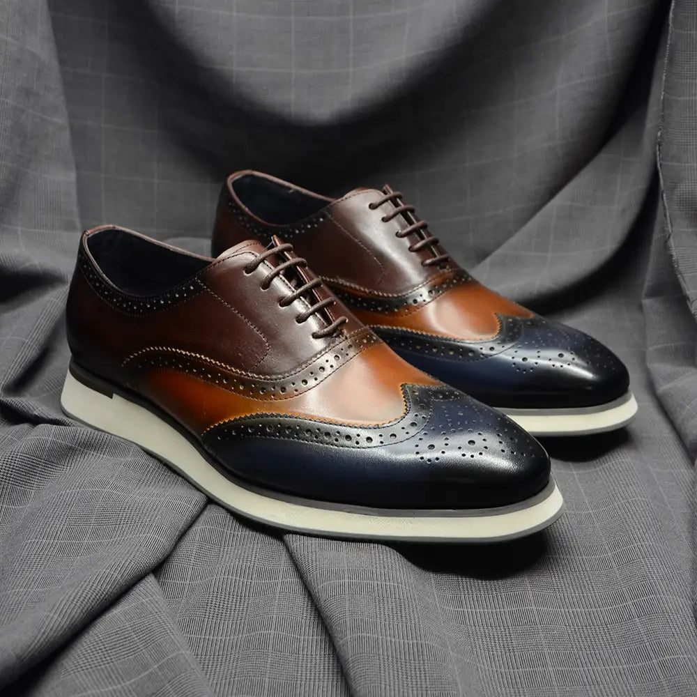 Escarpins brogue wingtip en cuir marron et bleu marine bicolore, avec des détails ajourés.