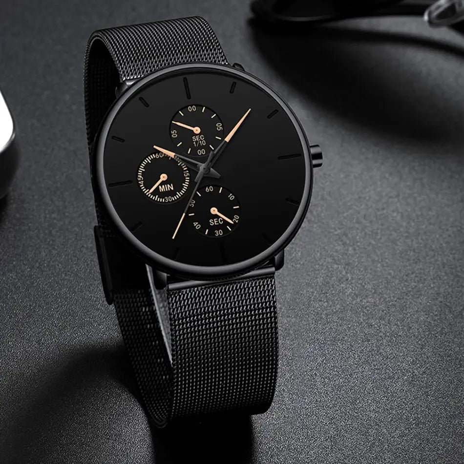 Montre à quartz à maille noire ultrafine pour hommes, avec un bracelet en maille d’acier inoxydable noir, un design minimaliste comprenant trois sous-cadrans et des aiguilles ton or.
