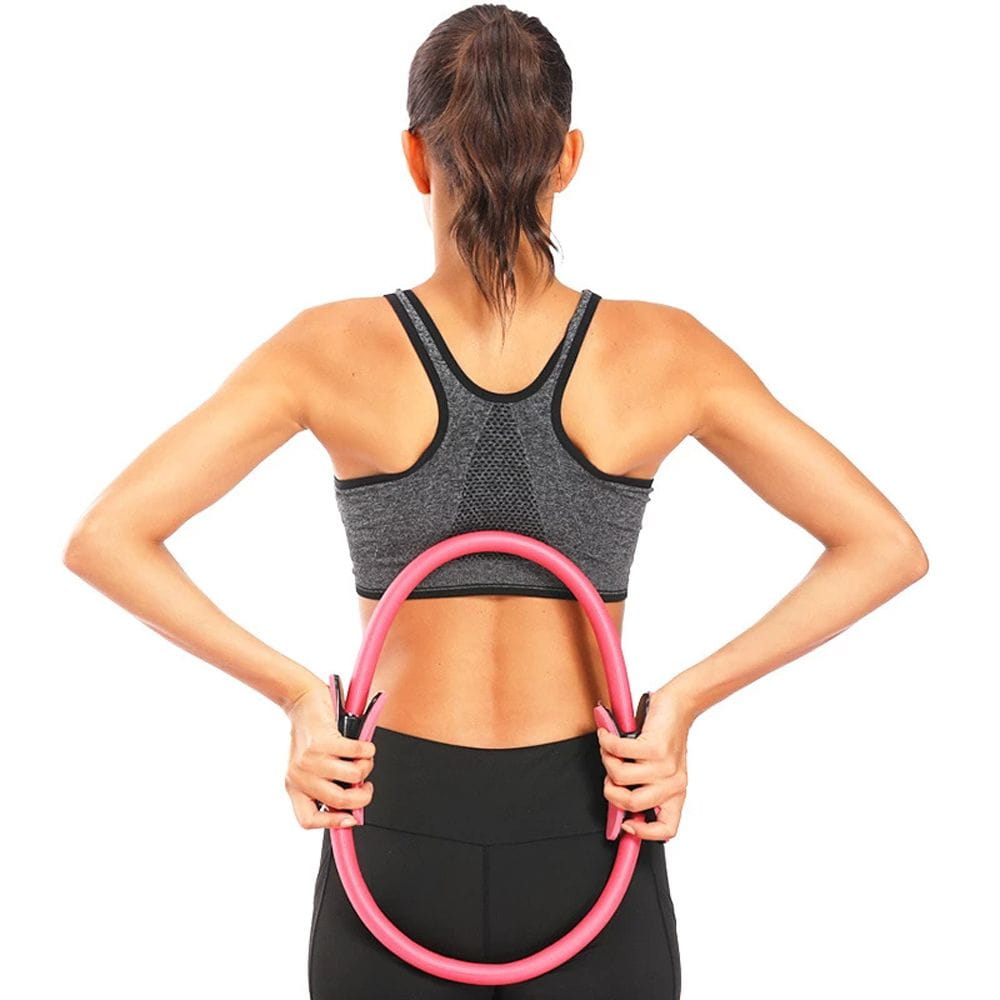 A woman holding a pink inflatable pilates ring designed as fitness magic circle yoga equipment for exercise and body toning.