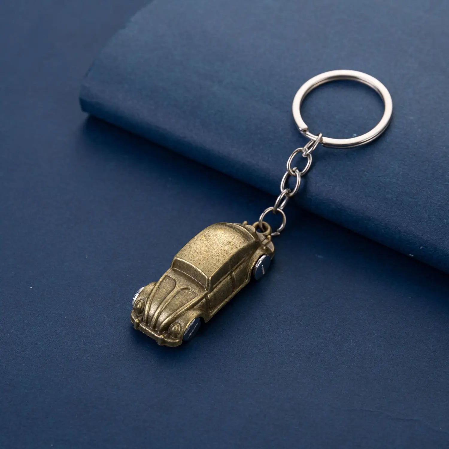 Golden brass Volkswagen Beetle metal car keychain featuring a silver metal ring and chain for secure attachment.