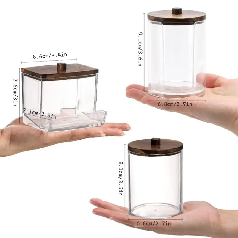Clear glass acrylic Q-tip and cotton ball storage jars with dark brown wooden lids and small black knobs.