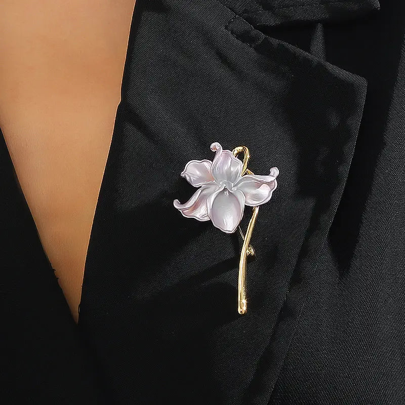 Une broche-épingle émaillée en forme de fleur de lotus délicate à ton argent et or, avec des pétales translucides.