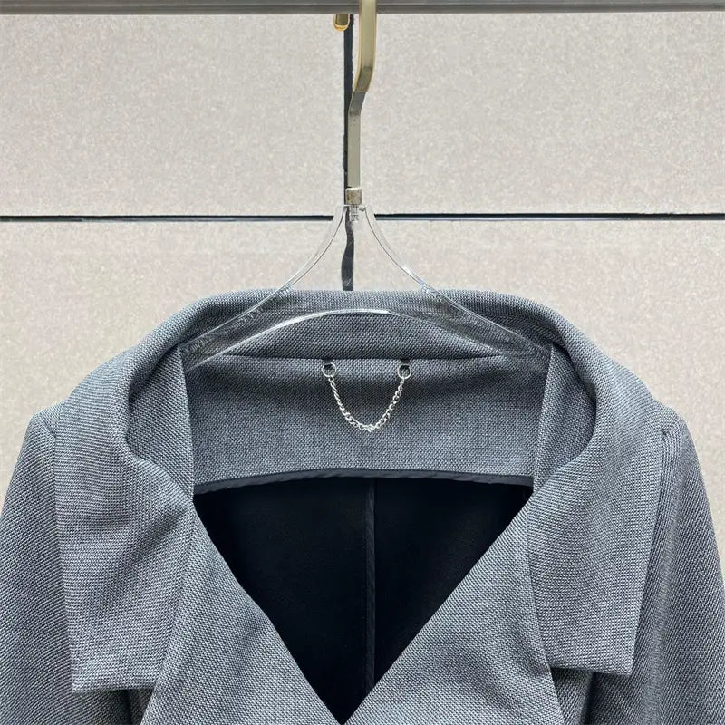Jupe crayon grise taille haute de longueur genou au style Y2K associée à un manteau en laine grise texturée comportant une doublure intérieure noire et un détail délicat de chaîne argentée au niveau du col