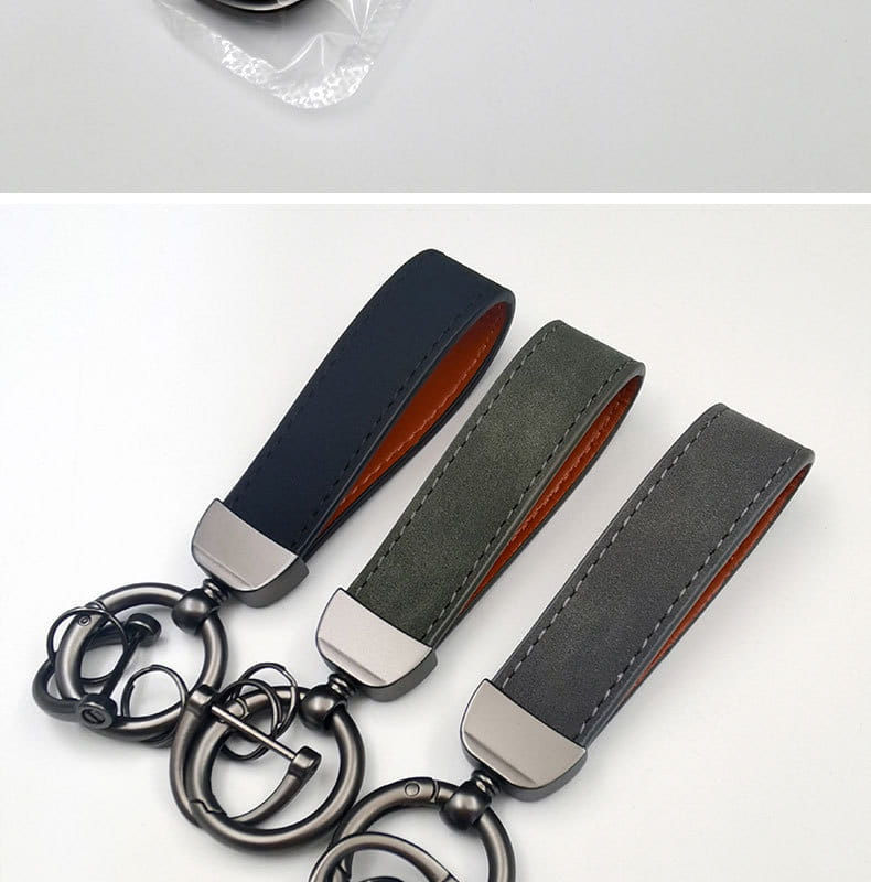 Three genuine leather keychains with matte-finished navy olive green and charcoal gray straps featuring contrasting orange lining and silver-toned metal hardware for car keys.