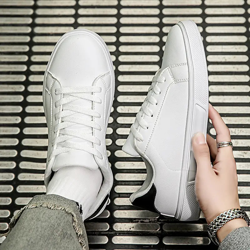 Weiße Ledersneaker im Freizeitstil, leichte Sportschuhe, mit schwarzen Akzenten an Ferse und Zunge, in einem klaren minimalistischen Design.
