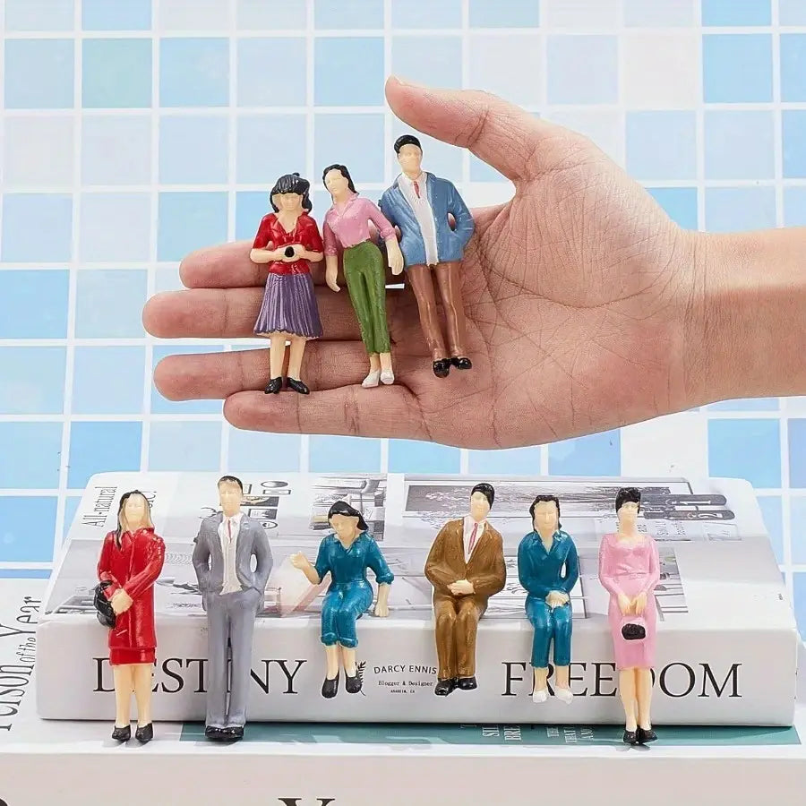A hand holds five miniature plastic model train sitting passengers painted dolls in colorful detailed outfits.