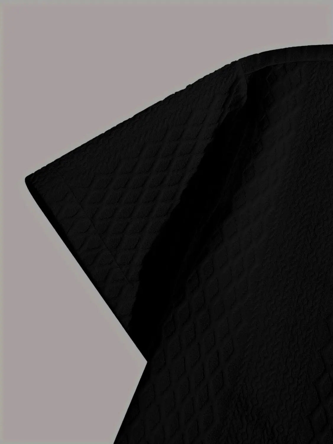 tissu noir texturé avec un motif matelassé discret présenté sur le haut gris en maille diamant à manches courtes