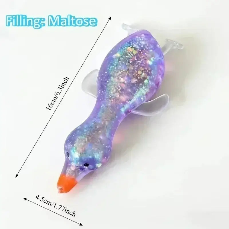 Un jouet à mâcher et à malaxer en forme de fromage translucide violet, en forme de dauphin, rempli de maltose et de paillettes, avec un bec orange vif, conçu pour apaiser le stress lié au jouet et pour soulager le stress.