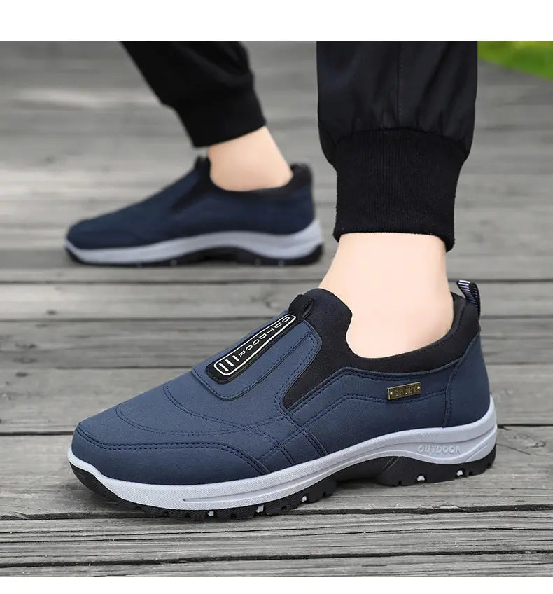 A navy blue orthopedic slip-on walking shoe for men with black accents and a white rubber sole designed for outdoor use.