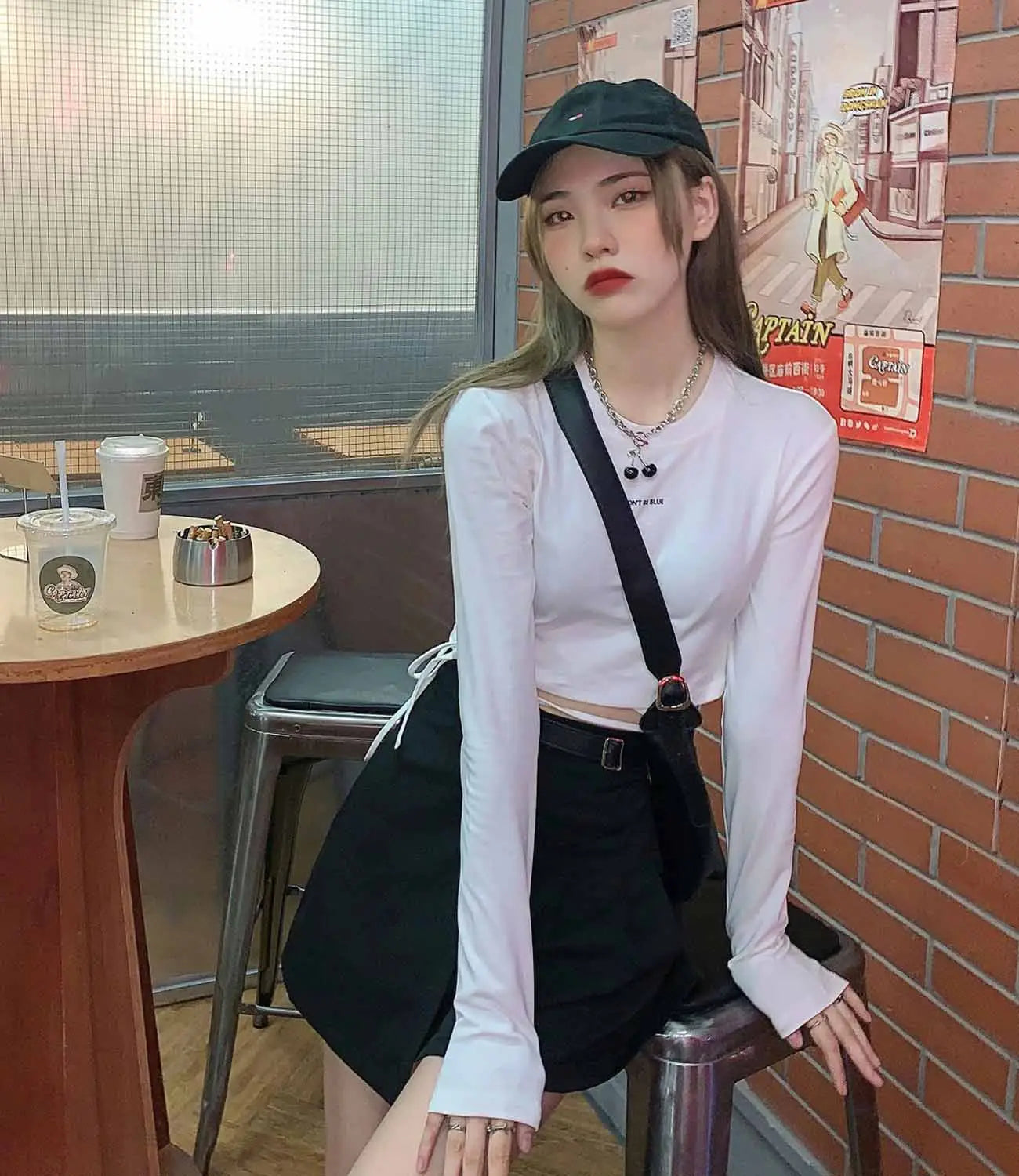Schwarze Umhängetasche mit einem Schulterriemen und runder Metallschnalle, kombiniert mit Damen-Langarm-Crisscross-Crop-Top