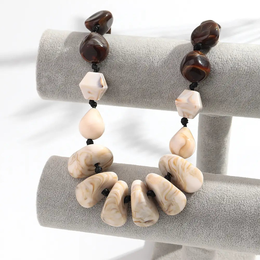 Collier ras du cou en résine à motif géométrique, fait de perles marbrées, au style élégant, avec alternance de perles lisses brun foncé et de pierres marbrées couleur crème, ainsi qu’une perle d’accent hexagonale.