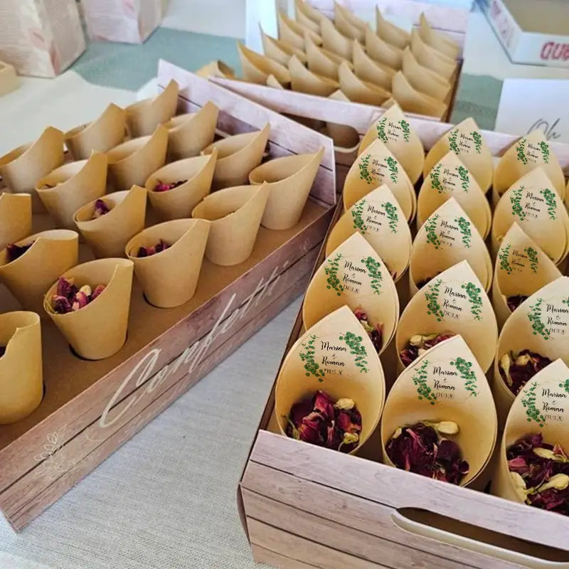 Personalisierte Hochzeits-Konfetti-Tüten, 30 Stück, mit weißen Papiertüten, gefüllt mit getrockneten Rosenblütenblättern und Grünzeug, verziert mit gedruckten Etiketten mit den Namen marina und roman sowie dekorativen Blattmotiven.