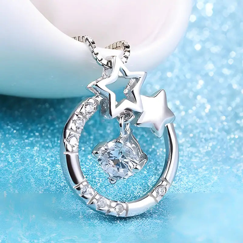 Collier pendentif en zircon plaqué argent sterling pour femmes, présentant un croissant de lune en argent orné de cristaux transparents scintillants et de breloques en forme d’étoile pendantes.