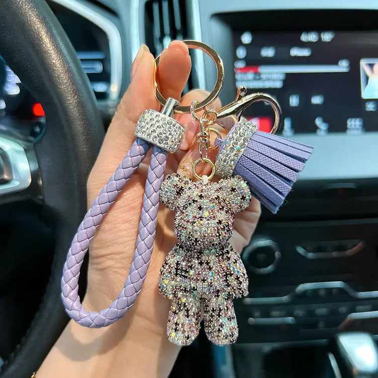 A lavender braided leather keychain featuring a rhinestone-covered bear charm and matching tassel for stylish accessory organization.