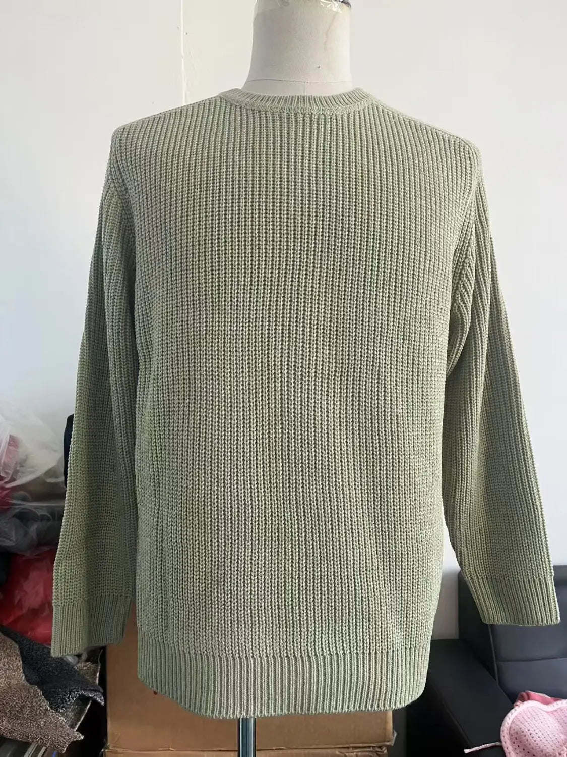 Ein weicher olivgrüner Rippstrick-Chunky-Pullover mit klassischem Crewneck und langen Ärmeln, auf einer Schaufensterpuppe für einen lässigen Look präsentiert.