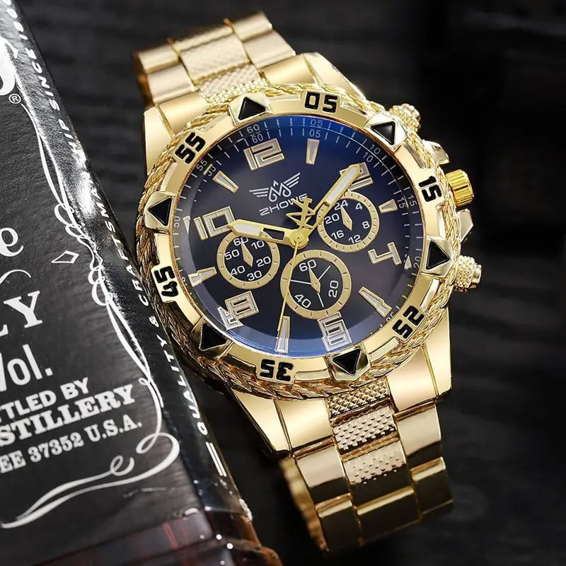 Montre à quartz à chronographe en acier inoxydable Tvk avec un boîtier en acier inoxydable couleur dorée, un cadran bleu profond, des marqueurs horaires triangulaires noirs, et trois sous-cadrans.