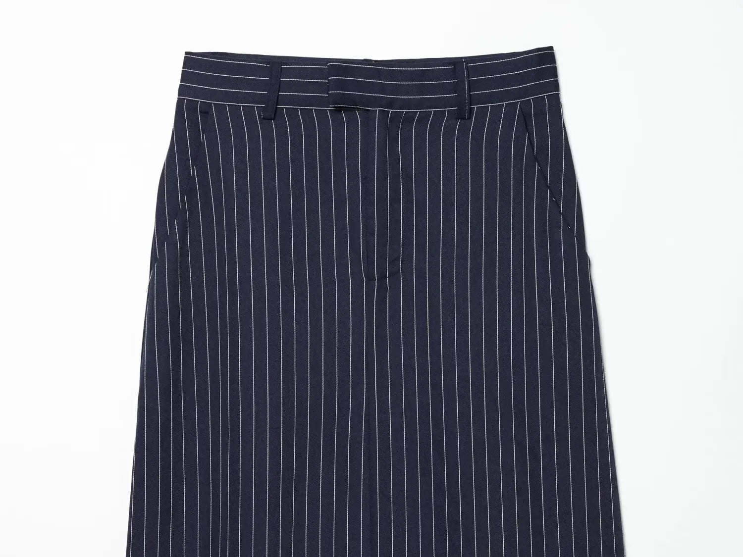 Pantalón azul marino de pinstripe con rayas verticales blancas y pretina a medida que se muestra de frente; está diseñado como parte de una colección de falda maxi de tiro alto.