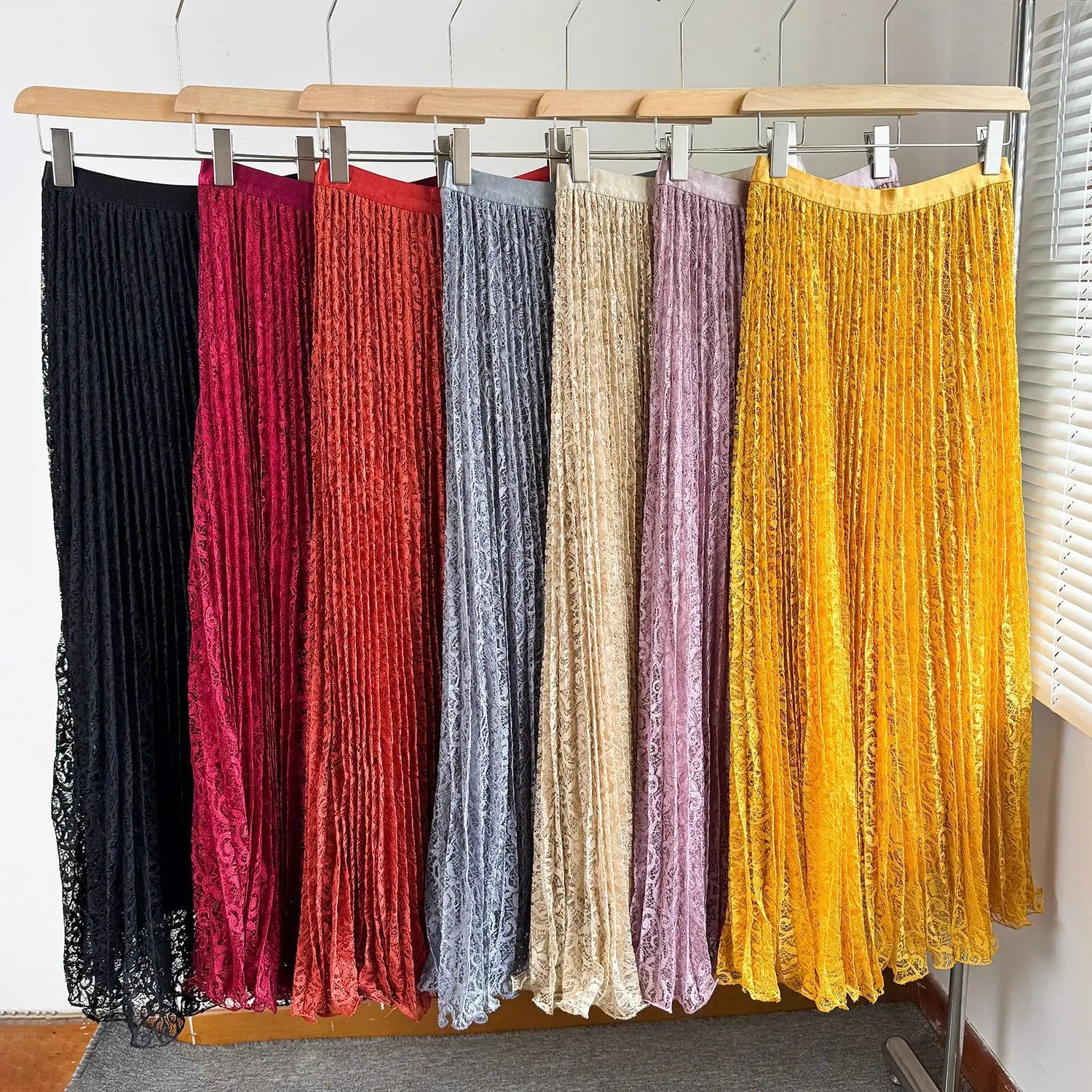 A collection of high waist pleated midi skirts made of lace in vibrant colors including black, red, blue, beige, purple, and yellow for y2k streetwear.