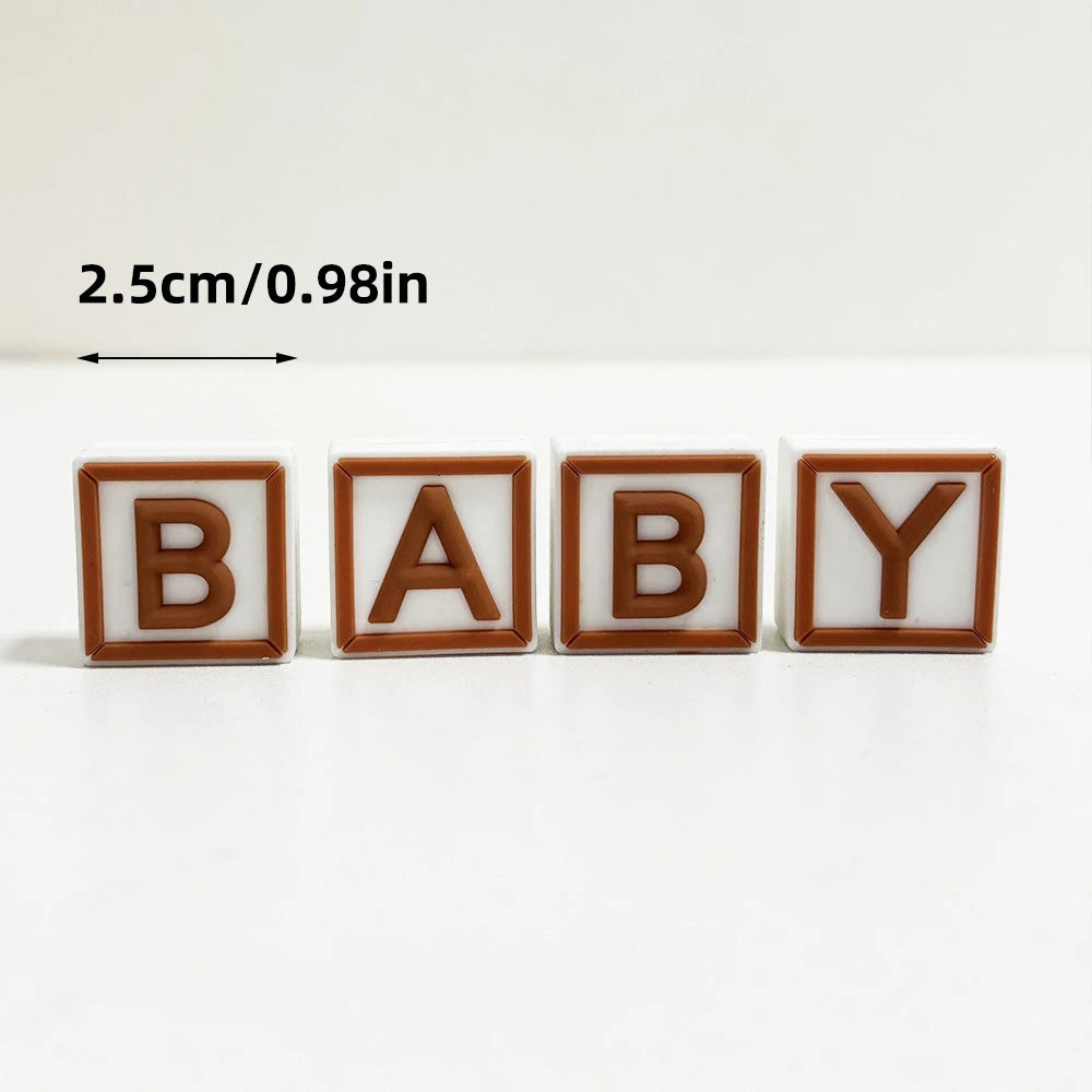 ミニベア ケーキトッパーセット。茶色と白の木製レターブロックで「baby」と綴り、浮き文字になっており、滑らかな表面で幅2.5cmです。