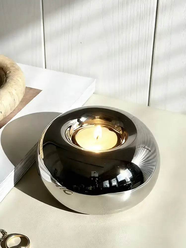 Silver ceramic sphere candle holder with shiny silver metallic smooth reflective surface and subtle radial grooves.