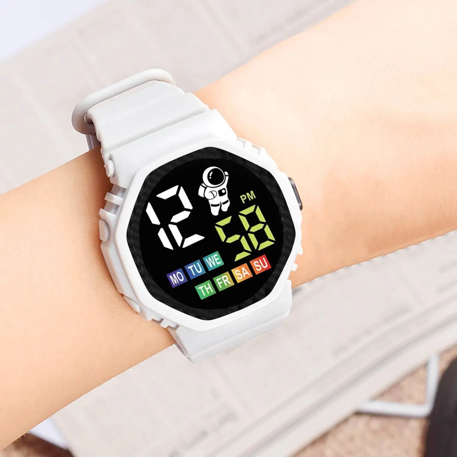 white kids waterproof led digital astronaut watch with octagonal case and strap featuring a black display with green time digits, an astronaut icon, and colorful day abbreviations.