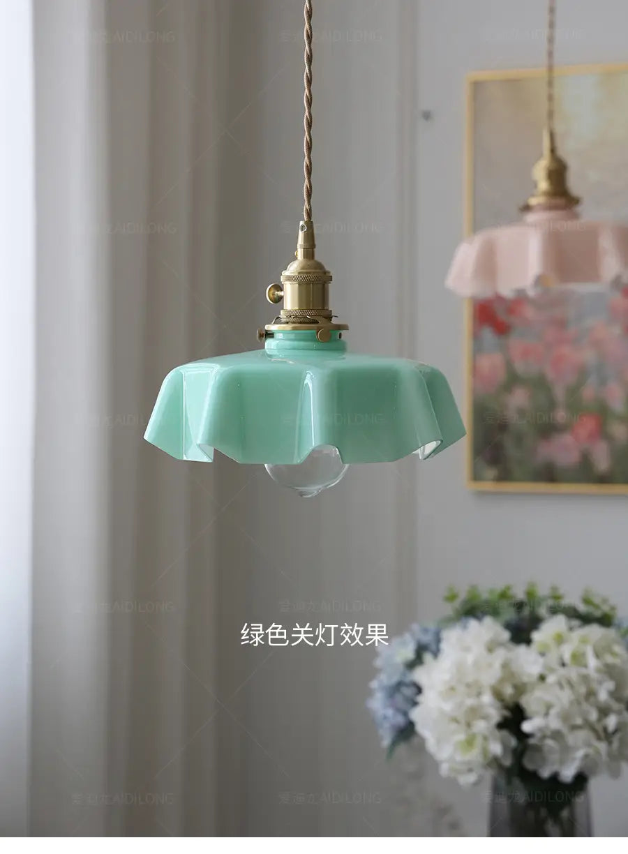Un luminaire délicat suspendu à jupe florale en verre vert menthe avec une conception froncée cannelée et une tête de lampe en cuivre visible depuis l’avant.