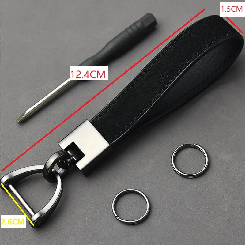 Black leather keychain with silver metal d-ring and rectangular connector alongside two small rings and a screwdriver in a leather keychains set multicolor metal clasp.