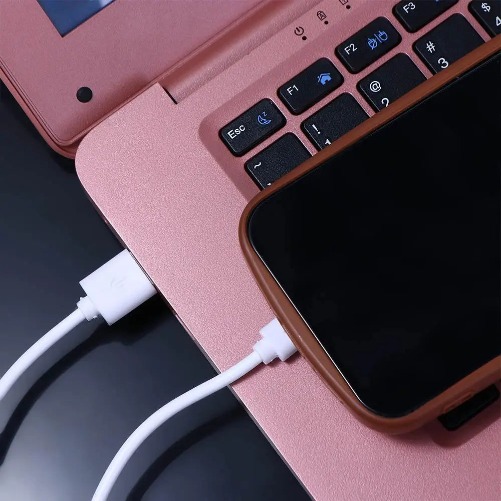 Cable blanco micro USB de carga rápida conectado a un ordenador portátil y un teléfono inteligente en color dorado rosa para una carga eficiente del dispositivo