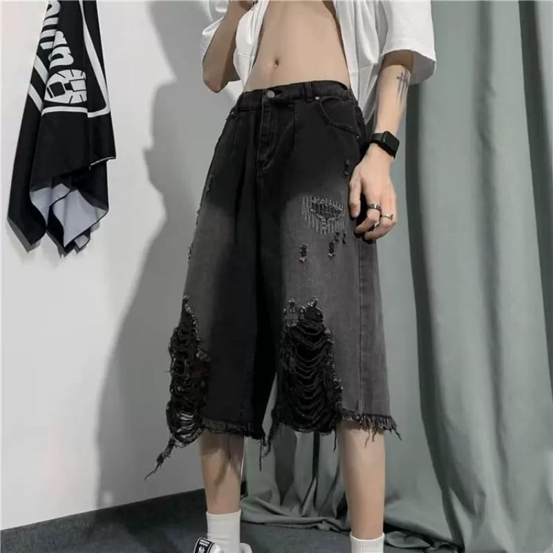 黒のダメージ加工デニムのメンズワイドレッグジーンズで、脚にフリル状の重ね合わせリップ（破れ）ディテールが施されており、ビンテージストリートウェアに適しています。