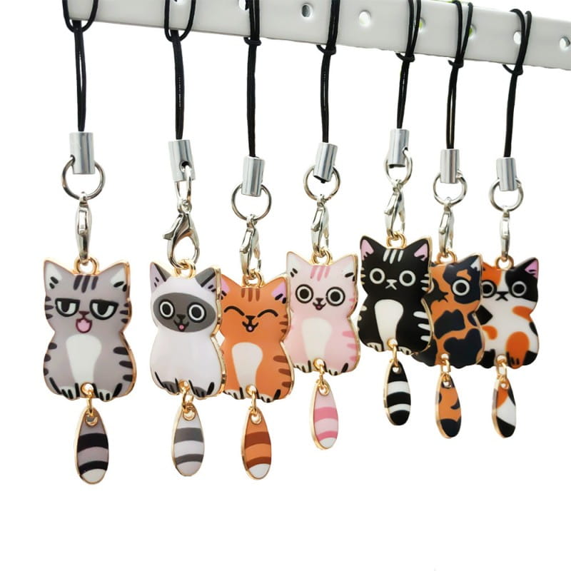 A collection of colorful cartoon-style enamel cat keychains with dangling striped tails and playful charm designs.
