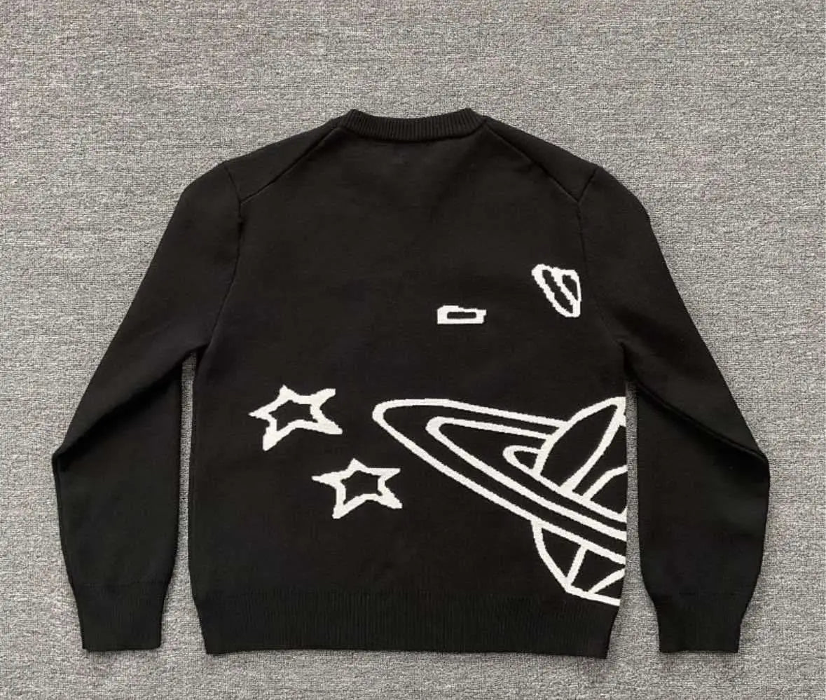 suéter de punto negro con diseño bordado en blanco de estrellas de Saturno y pequeñas naves espaciales, presentado en el frente en el suéter de punto con bordados y gráfico