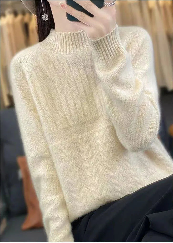 Cream-colored women’s wool knit pullover sweater with long sleeves, ribbed high neckline, and intricate cable-knit pattern across the front.