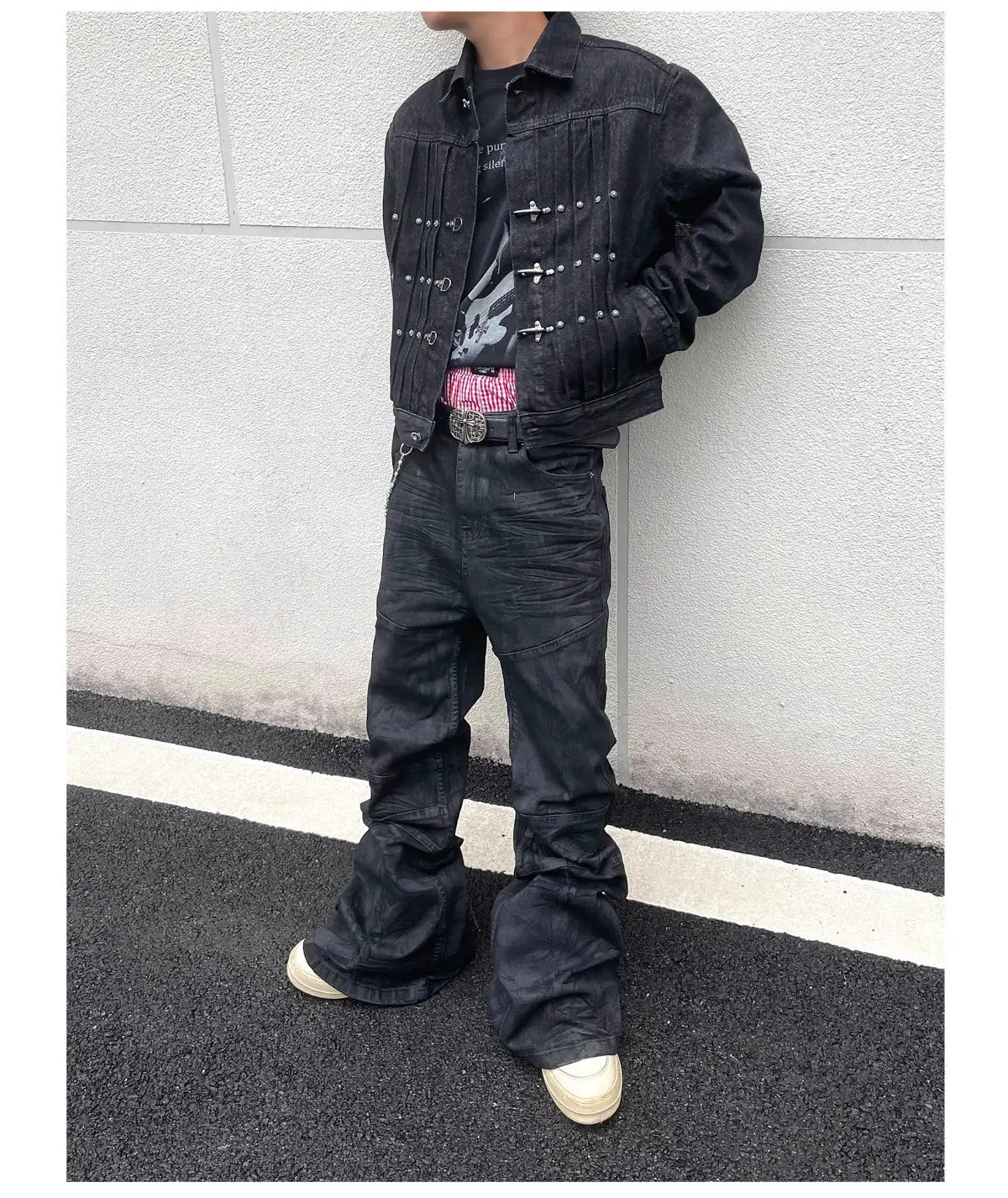 Veste en denim noire avec des fermetures à pression à tons argentés et des clous décoratifs le long de la patte avant, associée à des jeans empilés en denim noir Y2k vintage pour hommes.